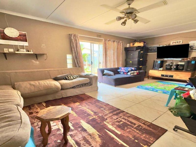 Spacious living room featuring tiled flooring, a ceiling fan, and a sliding glass door providing access to the outdoor area.