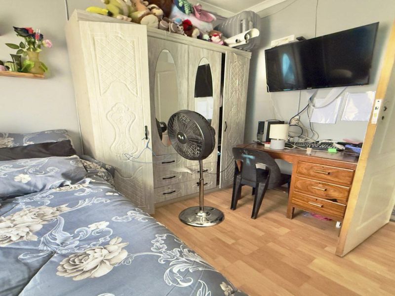 A functional bedroom featuring laminate flooring and a built-in wardrobe, providing practical storage space within the room.