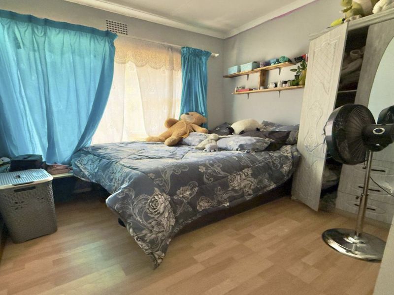 A standard bedroom featuring laminate flooring, coved ceiling details, and wall-mounted shelving, providing a functional living space.