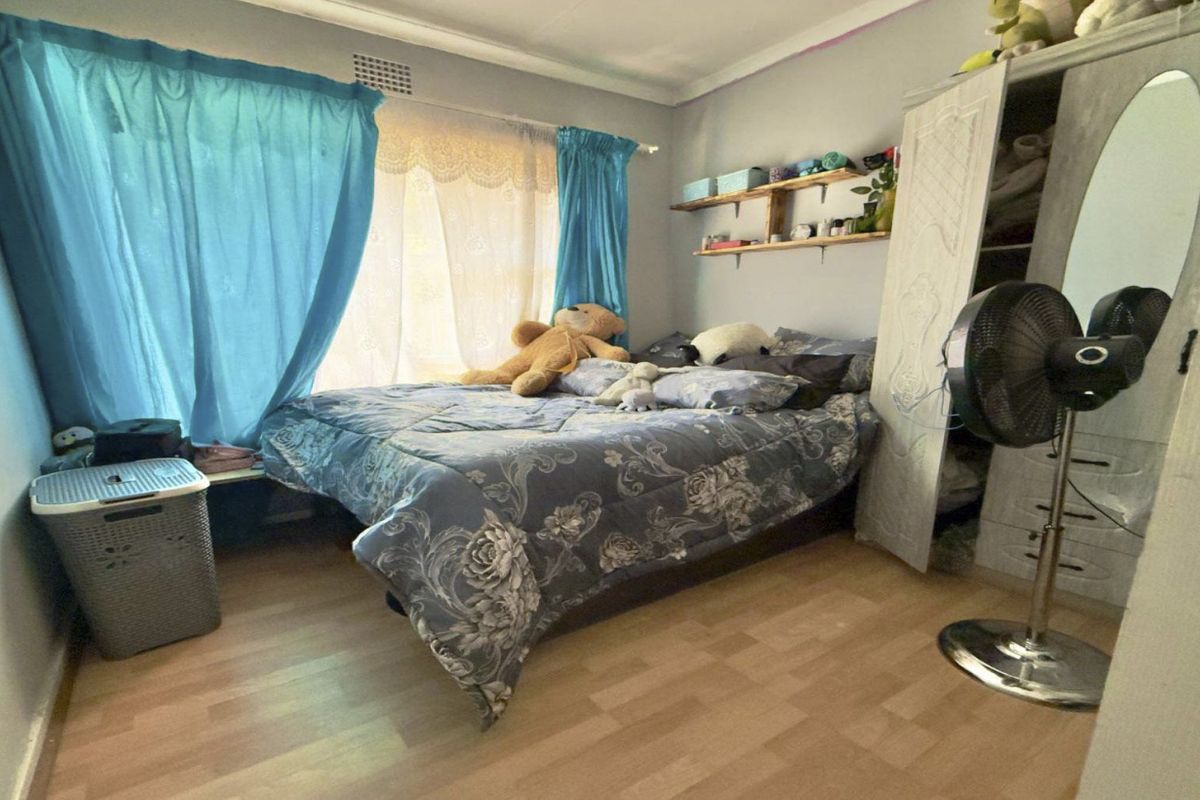 A standard bedroom featuring laminate flooring, coved ceiling details, and wall-mounted shelving, providing a functional living space.
