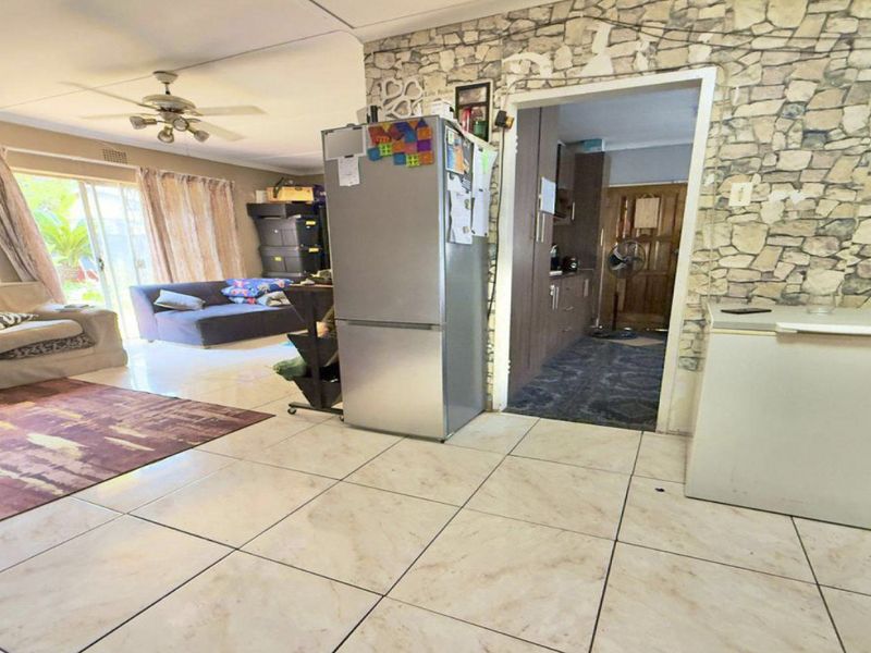 Open plan living area featuring tiled floors, a stone veneer feature wall, and access to the outdoor area via sliding glass doors.