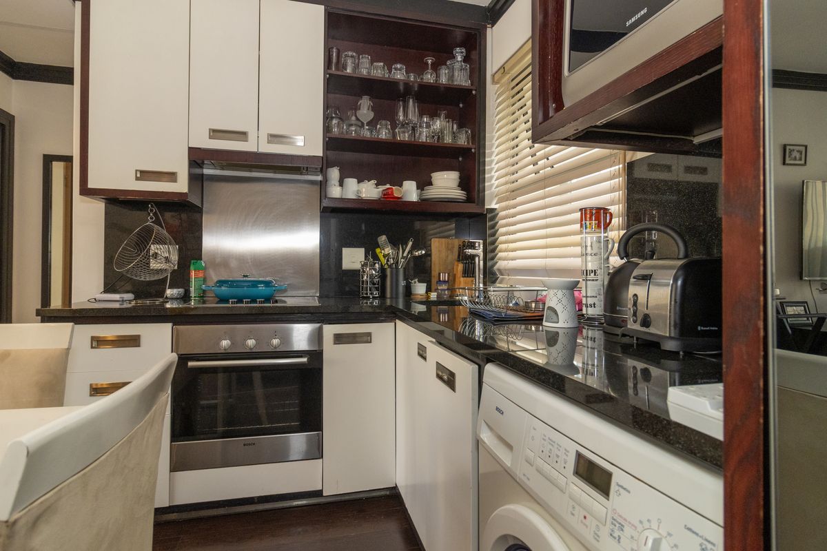 Compact kitchen featuring dark granite countertops, white cabinetry, stainless steel oven, and integrated microwave with a functional layout.