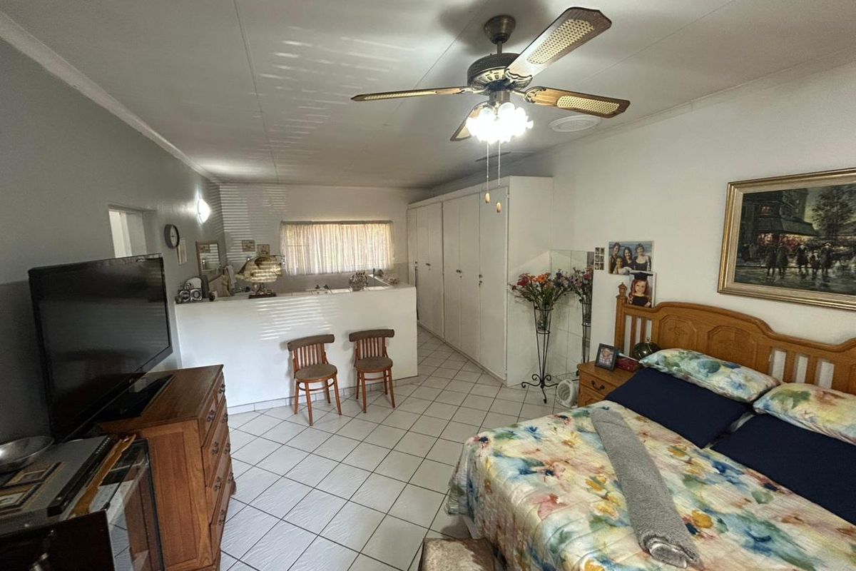 Spacious bedroom featuring tiled flooring, a ceiling fan, and extensive built-in cupboard storage.