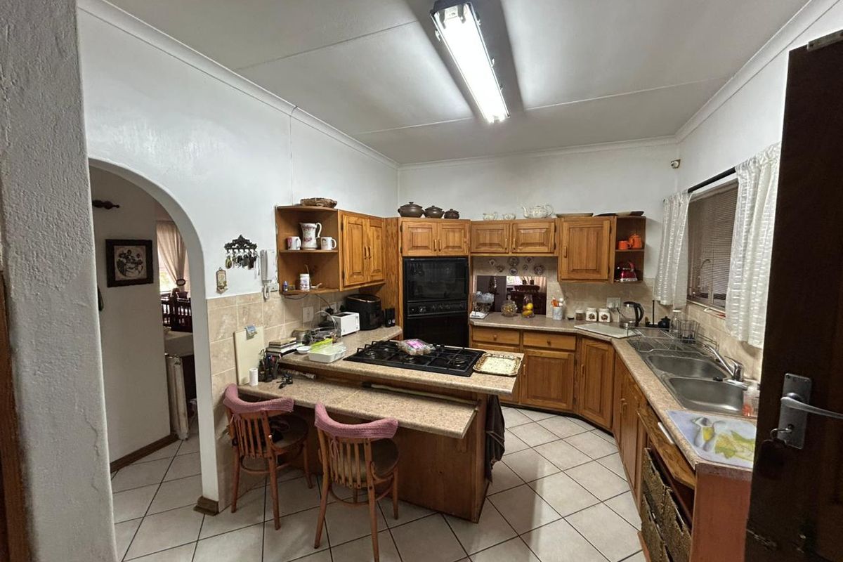 A functional kitchen featuring traditional wooden cabinetry, a built-in oven, gas hob, and tiled flooring, offering a classic layout with potential for modern updates.