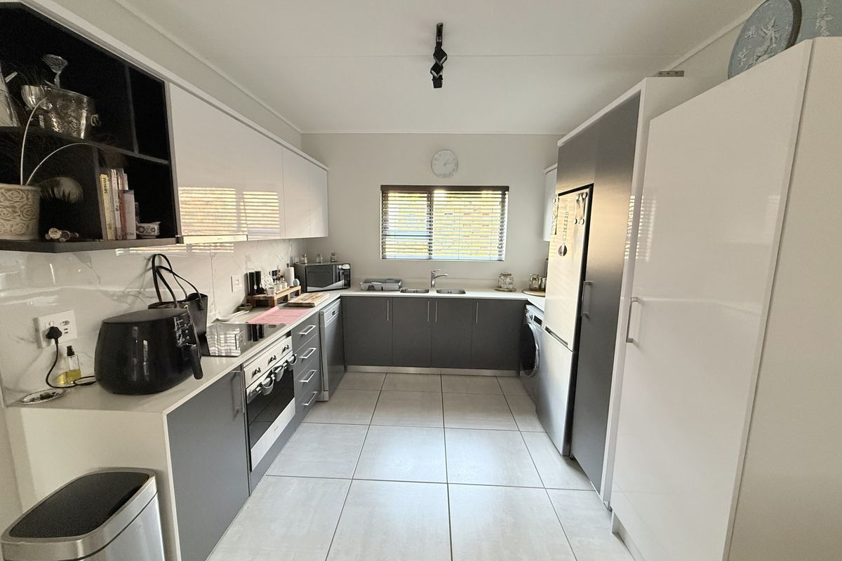 Modern kitchen featuring sleek two-tone cabinetry, integrated appliances, tiled flooring, and a functional layout with ample storage and workspace.