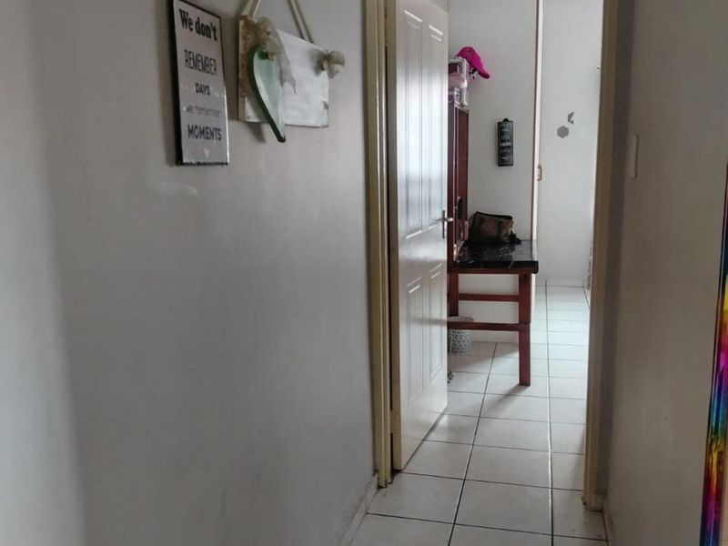 A functional hallway with tiled flooring leading to an adjacent room, featuring neutral wall finishes and standard internal door access.
