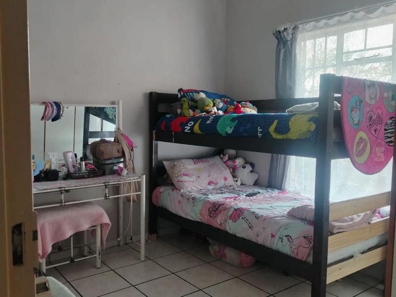 A bedroom featuring tiled flooring and a window, currently utilized as a children's room with bunk beds.