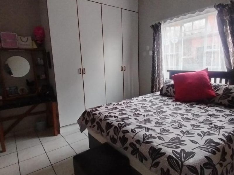 A bedroom featuring built-in cupboards, a ceiling fan, and tiled flooring, providing a functional living space.