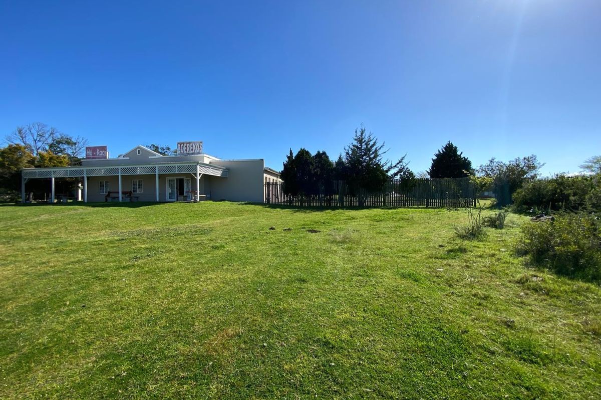 A view of the rear exterior of the farm building, featuring a covered patio area and expansive surrounding lawn.