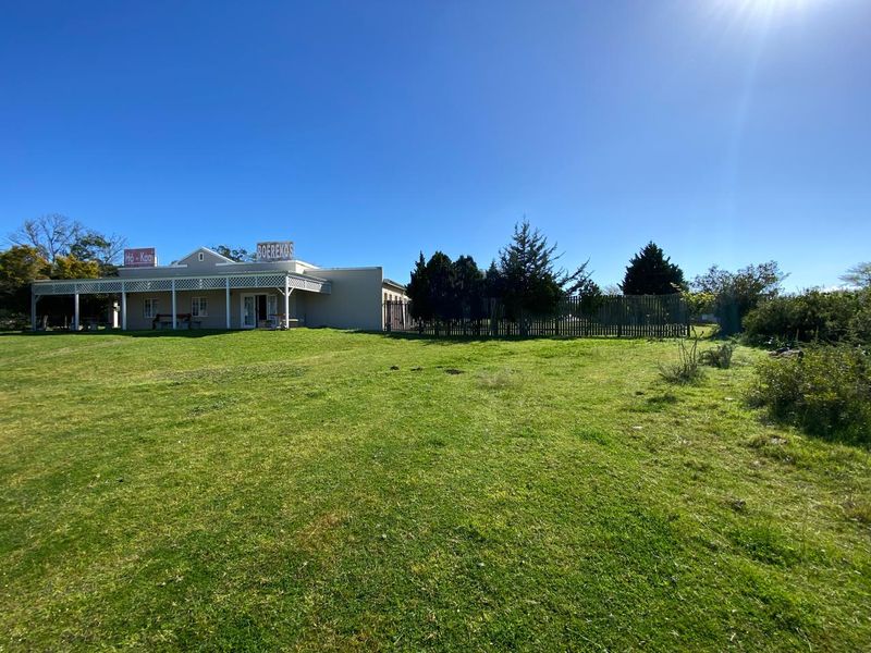 A view of the rear exterior of the farm building, featuring a covered patio area and expansive surrounding lawn.