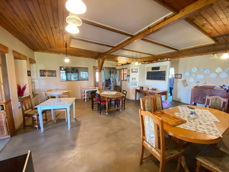 Spacious dining area featuring exposed timber ceiling beams, tongue and groove wood paneling, and durable concrete flooring.