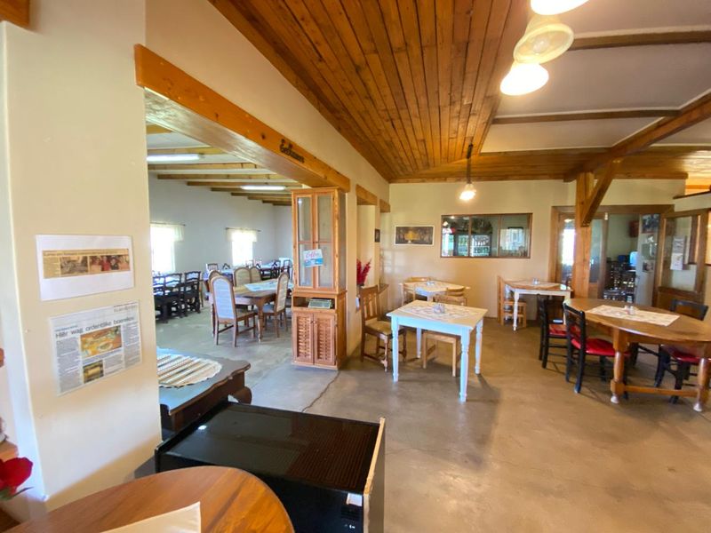 Spacious open-plan dining area featuring exposed timber ceiling beams, tongue and groove timber ceilings, and durable concrete flooring.