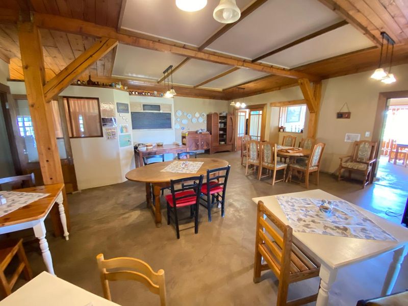 Spacious open-plan dining area featuring exposed timber beams, rustic concrete flooring, and a warm, traditional farm-style aesthetic.