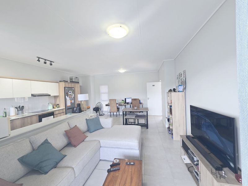 Spacious open-plan living area featuring a modern kitchen with built-in cabinetry, tiled flooring, and a seamless flow to the dining and lounge space.