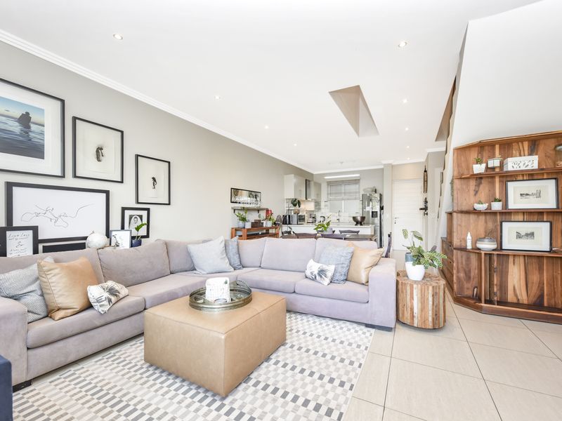 Spacious open-plan living area featuring tiled floors, recessed lighting, a skylight, and integrated kitchen cabinetry, creating a bright and functional living space.