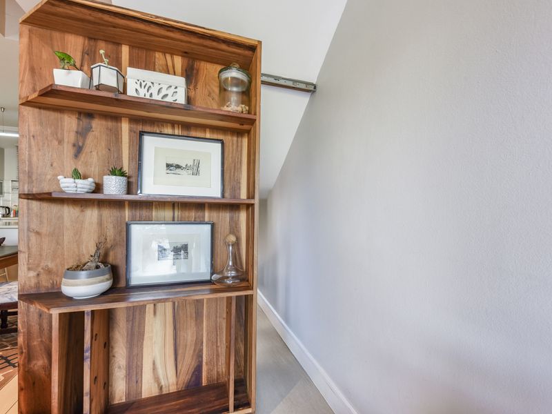A view of an open-plan living area featuring a custom built-in wooden shelving unit and a sloped ceiling design.