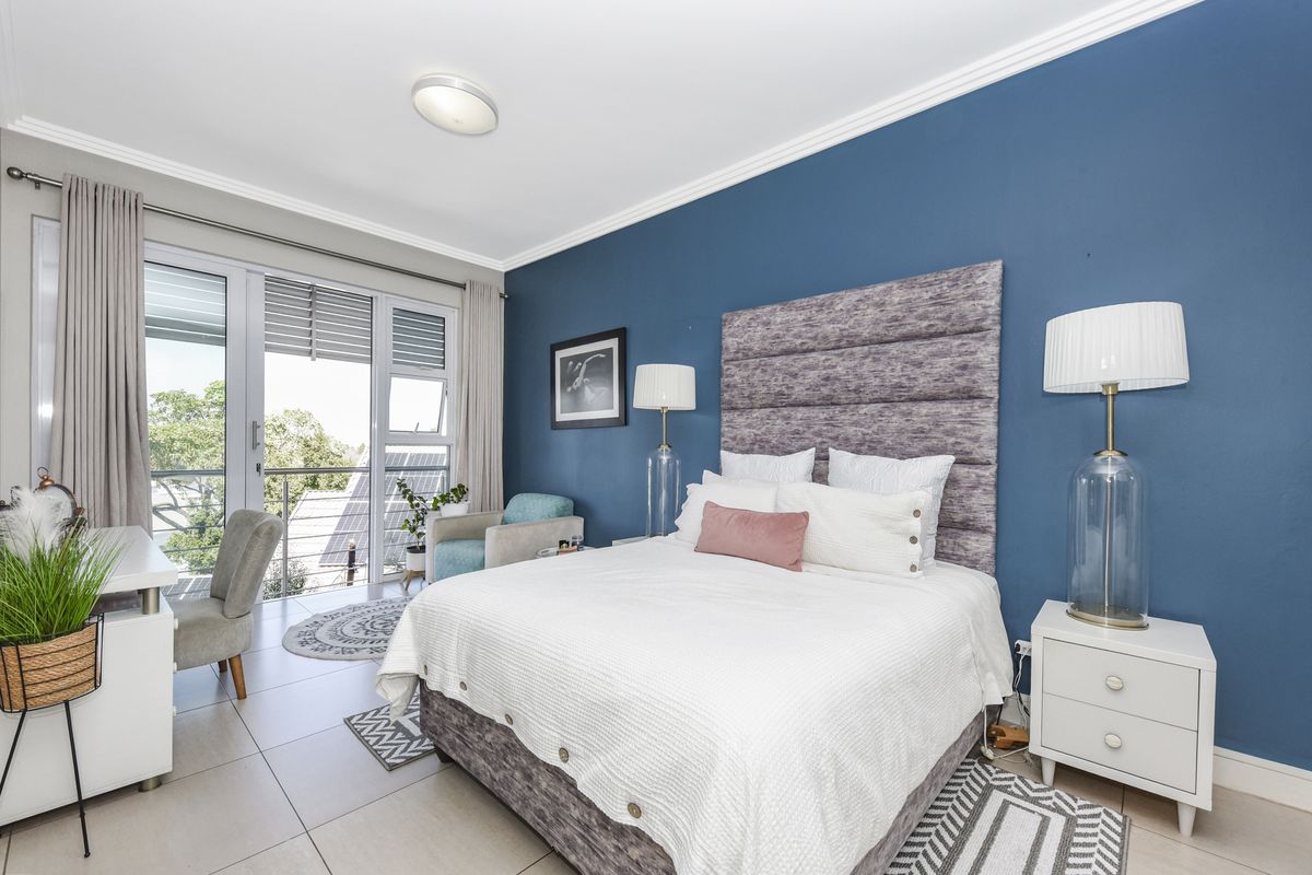 A well-lit bedroom featuring tiled floors, crown molding, and a large sliding glass door providing access to an outdoor balcony area.