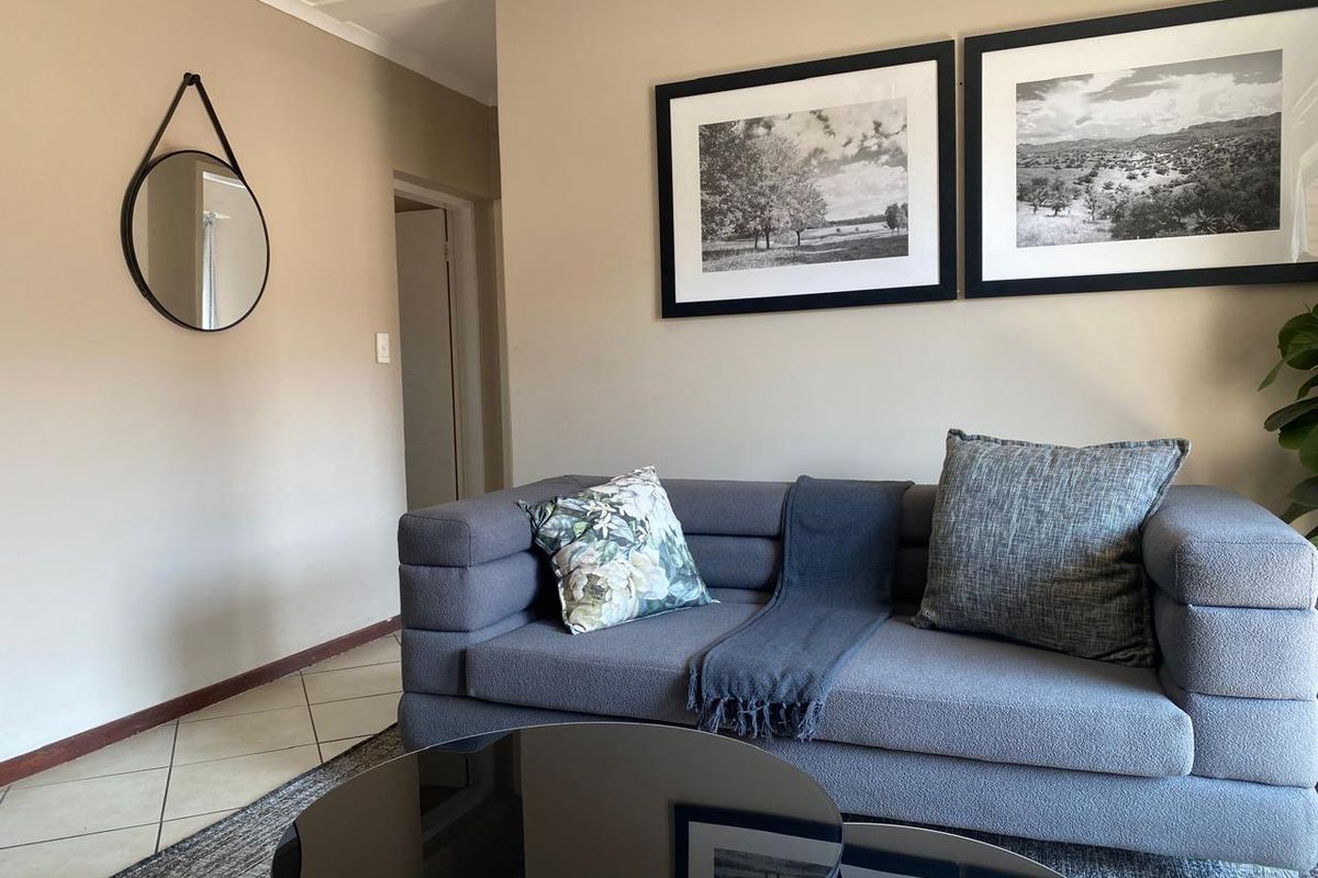 A well-maintained living room featuring neutral wall tones, tiled flooring, and coved ceiling details, creating a comfortable and inviting atmosphere.
