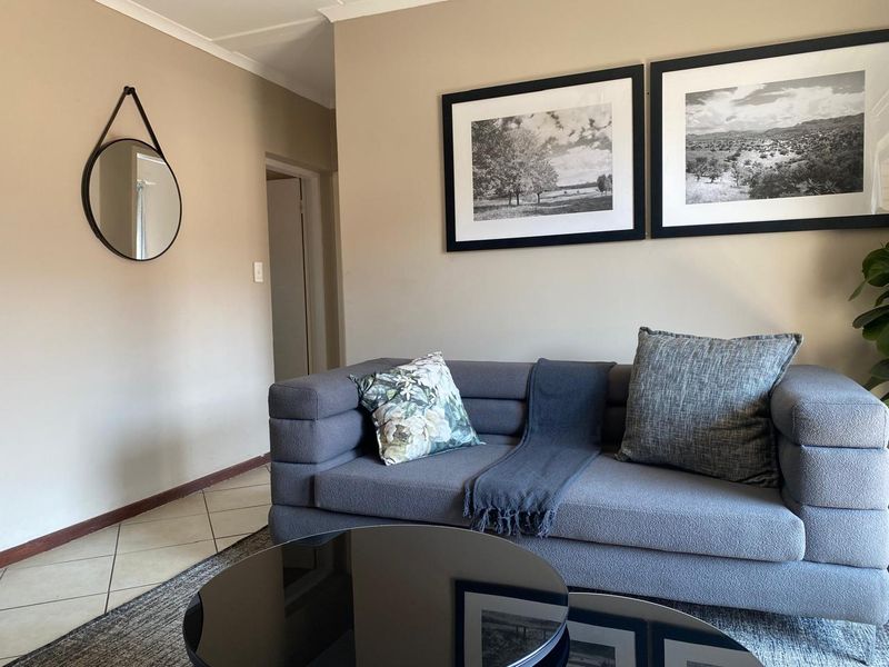 A well-maintained living room featuring neutral wall tones, tiled flooring, and coved ceiling details, creating a comfortable and inviting atmosphere.