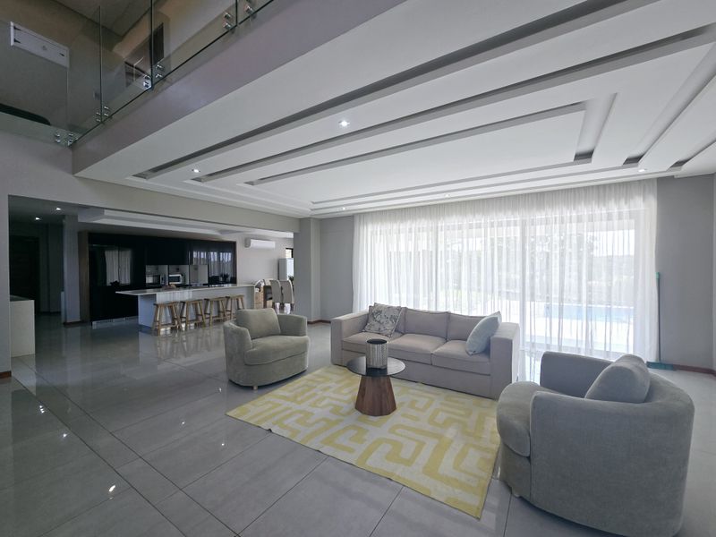 Spacious open-plan living area featuring modern recessed ceiling design, sleek kitchen cabinetry, large sliding doors, and high-quality tiled flooring throughout.