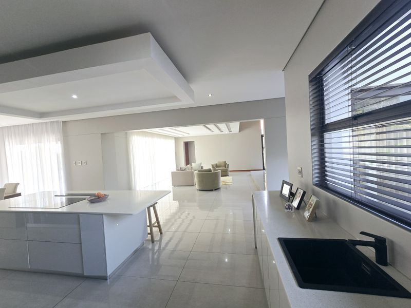Modern open-plan living area featuring a sleek kitchen with a central island, stone countertops, and high-quality finishes throughout the spacious, light-filled interior.