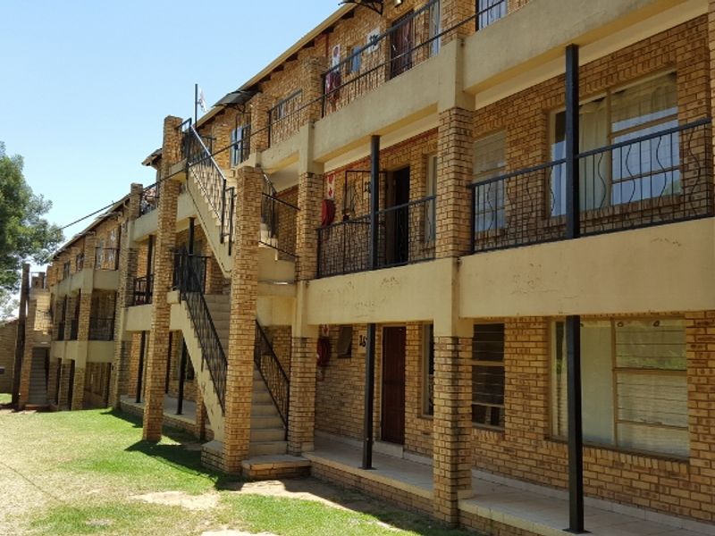 Exterior view of a multi-story apartment building featuring face brick construction, external staircases, and metal balcony railings.