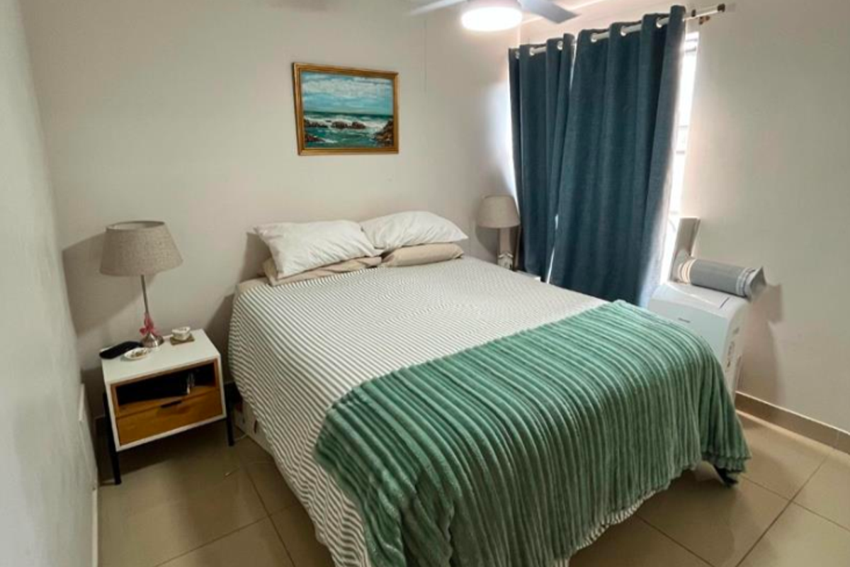 A functional bedroom featuring tiled flooring and a ceiling fan, providing a comfortable and neutral space.