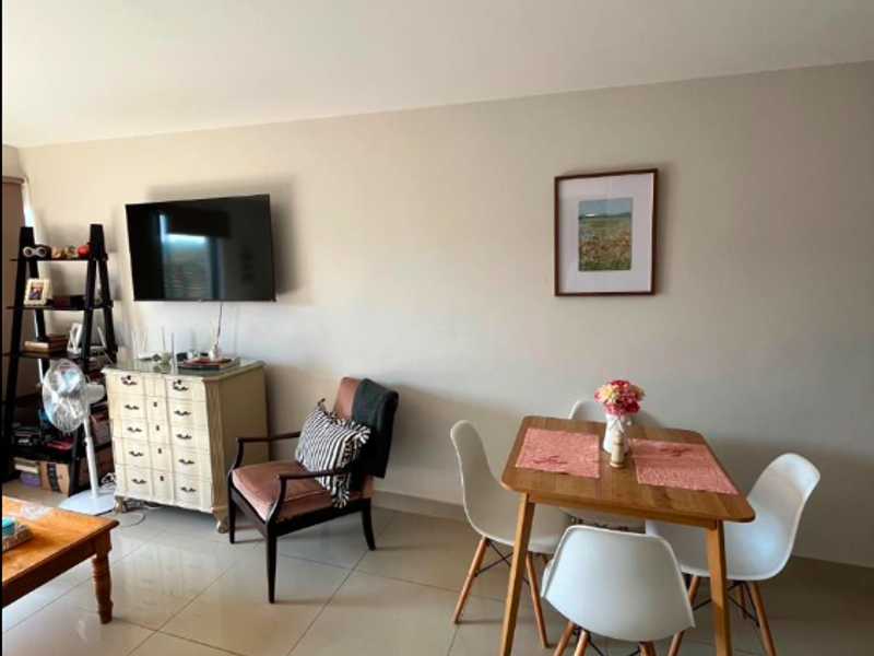 A bright living area featuring neutral wall tones and large format floor tiles, providing a clean and versatile space for relaxation and dining.