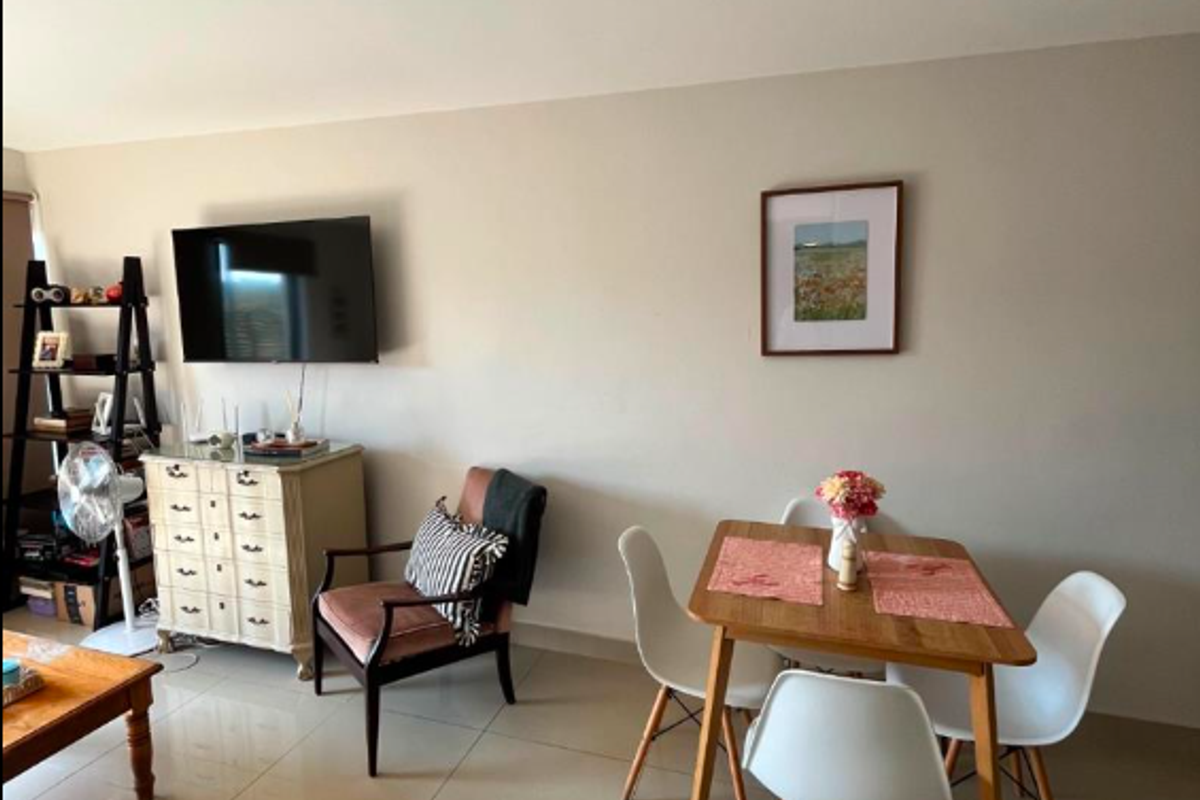 A bright living area featuring neutral wall tones and large format floor tiles, providing a clean and versatile space for relaxation and dining.