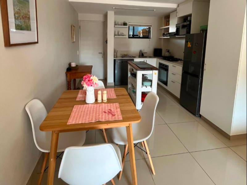 An open-plan kitchen and dining area featuring modern cabinetry, built-in appliances, and neutral tiled flooring throughout the space.