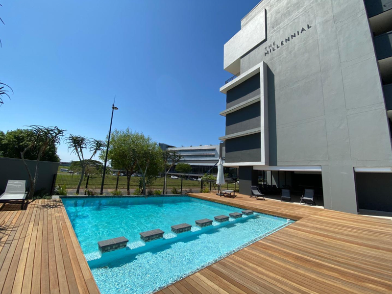 Modern apartment complex pool area featuring a clear swimming pool with integrated stepping stones and extensive timber decking.