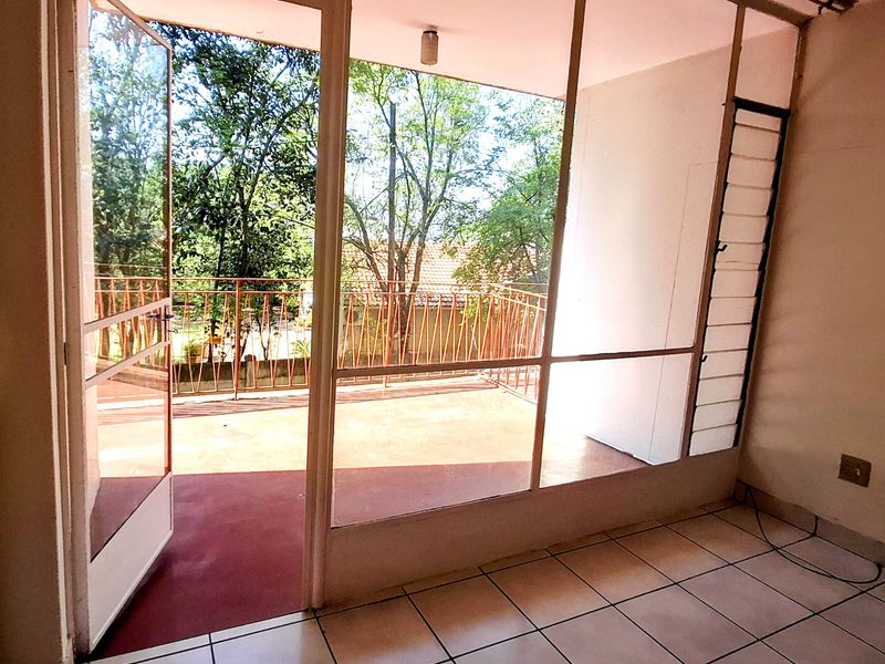 An empty balcony area featuring tiled flooring, a metal balustrade, and large glass doors providing access to the outdoor space.