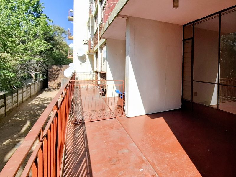 A spacious apartment balcony featuring a metal balustrade and painted concrete flooring, offering an outdoor area with potential for refurbishment.
