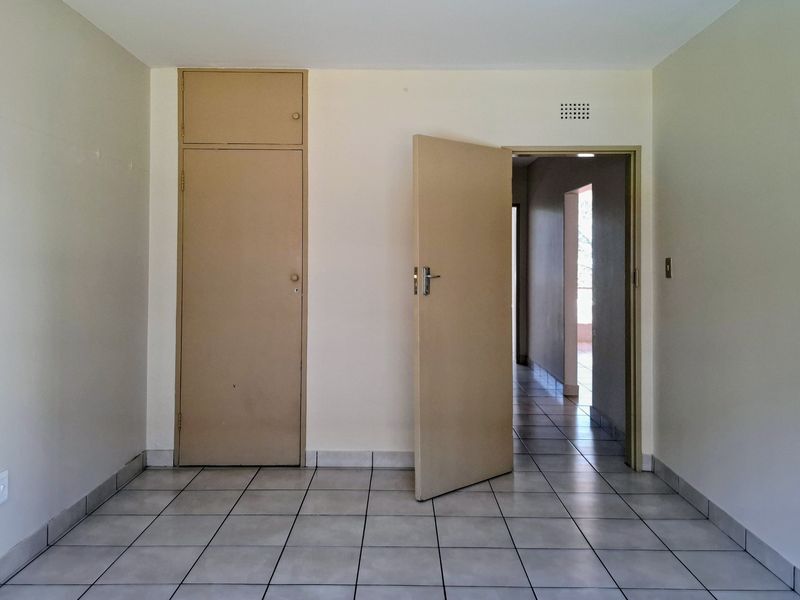An empty bedroom featuring tiled flooring and a built-in cupboard, providing a blank canvas for personalization.