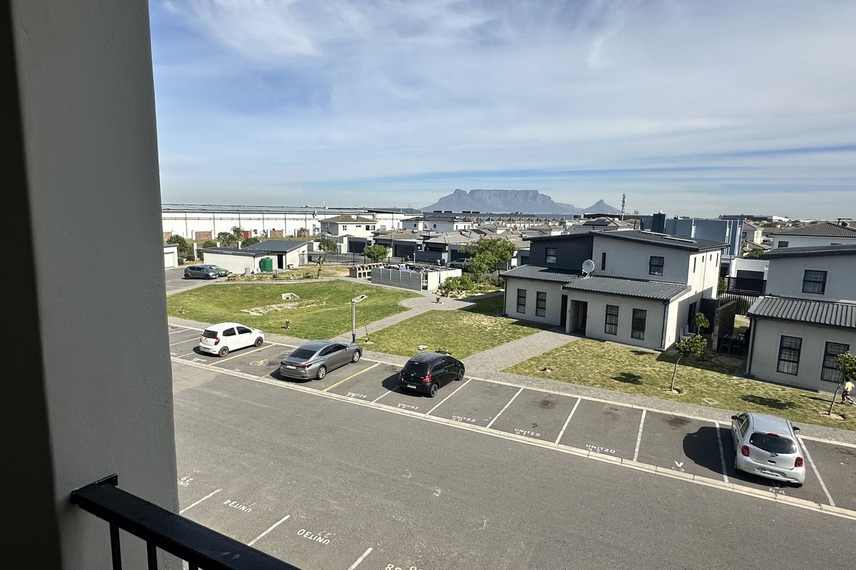 Elevated view overlooking the apartment complex parking area and communal lawn, featuring a clear view of Table Mountain in the distance.