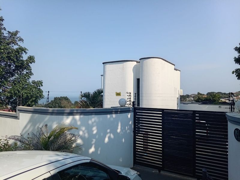 Front exterior view of the property featuring a secure perimeter wall with electric fencing and a modern sliding gate entrance.