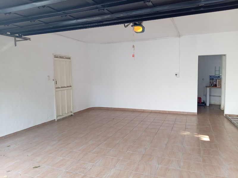 A clean, empty garage space featuring tiled flooring, an automatic door motor, and direct internal access to the home.
