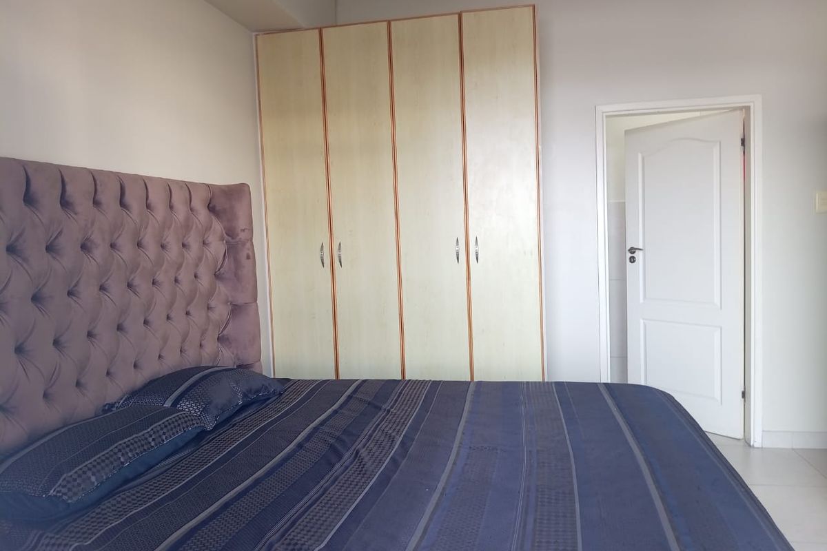A bedroom featuring built-in cupboards with light wood-finish doors and decorative ceiling coving.
