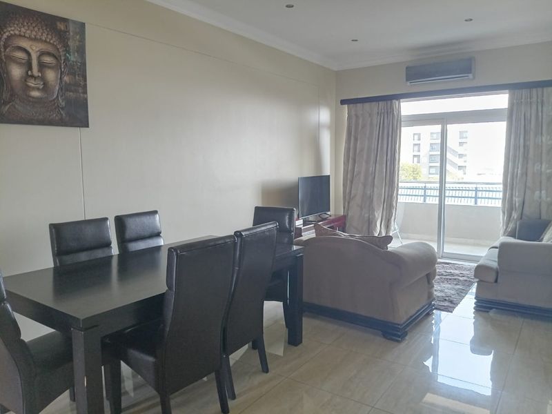 Open-plan living and dining area featuring tiled flooring, recessed lighting, and a sliding glass door leading to a balcony with air conditioning.
