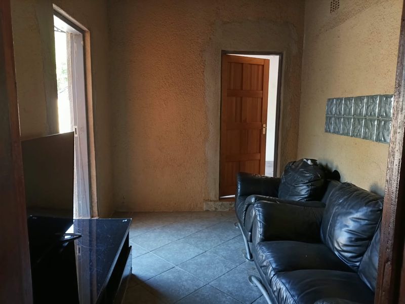 Living room featuring tiled flooring, textured walls, and a glass block accent, requiring finishing touches to the door frame and wall surfaces.