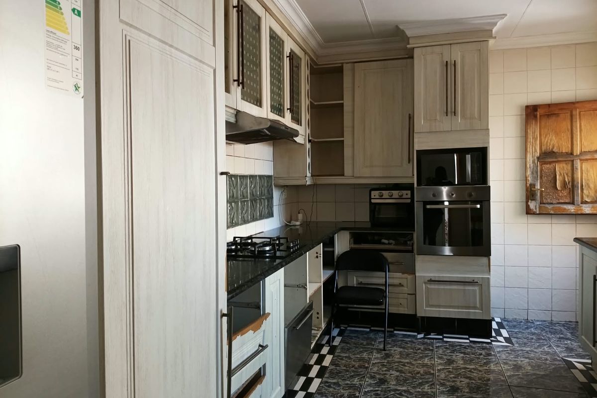 A functional kitchen featuring built-in cabinetry, granite countertops, a gas hob, and an integrated oven, with some visible wear on the cabinet finishes.