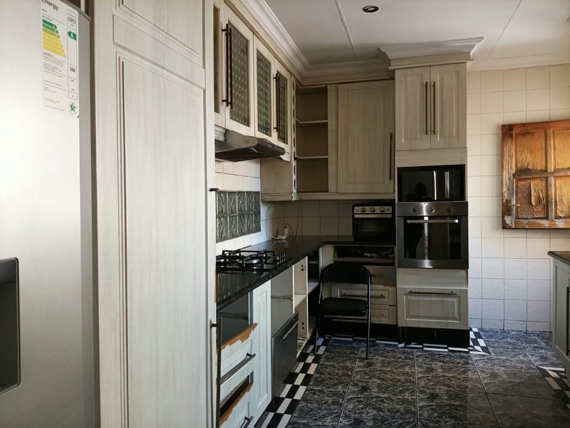 A functional kitchen featuring built-in cabinetry, granite countertops, a gas hob, and an integrated oven, with some visible wear on the cabinet finishes.