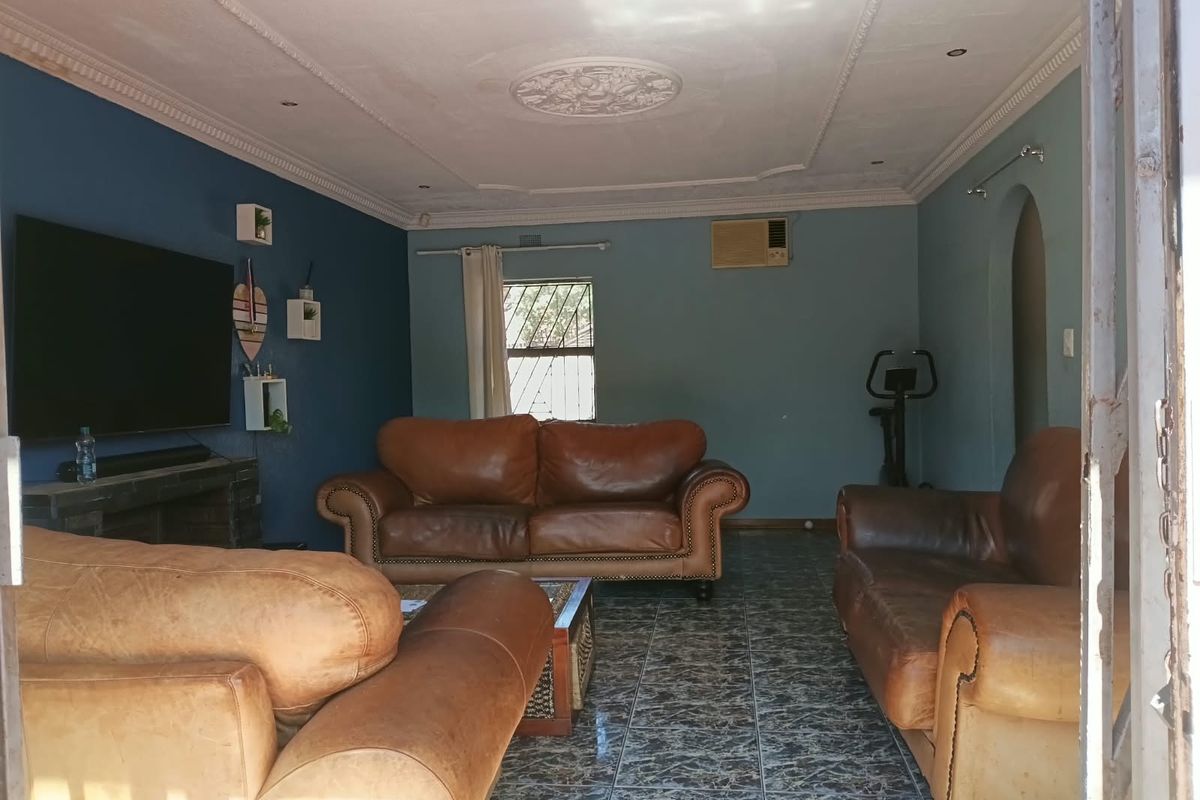 A living room featuring tiled flooring, decorative ceiling detailing, coved cornicing, and a wall-mounted air conditioning unit.