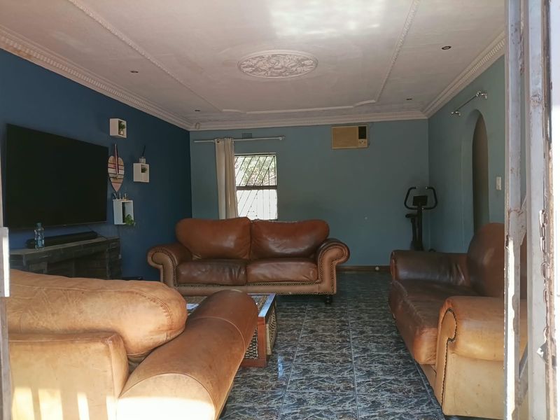 A living room featuring tiled flooring, decorative ceiling detailing, coved cornicing, and a wall-mounted air conditioning unit.