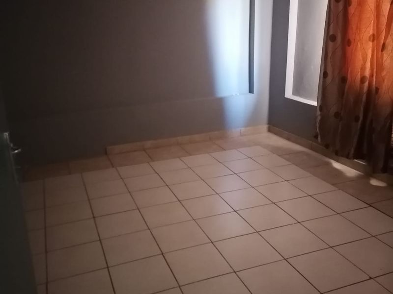 An empty bedroom featuring tiled flooring, a recessed wall niche, and neutral grey wall paint.