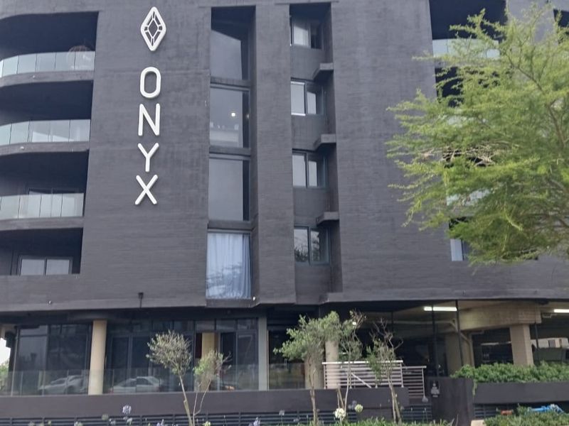 Modern apartment building facade featuring dark exterior finishes, glass balconies, and integrated street-level parking.