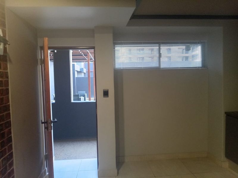 An interior entry area featuring tiled flooring, an exposed brick accent wall, and a doorway leading to an outdoor patio space.