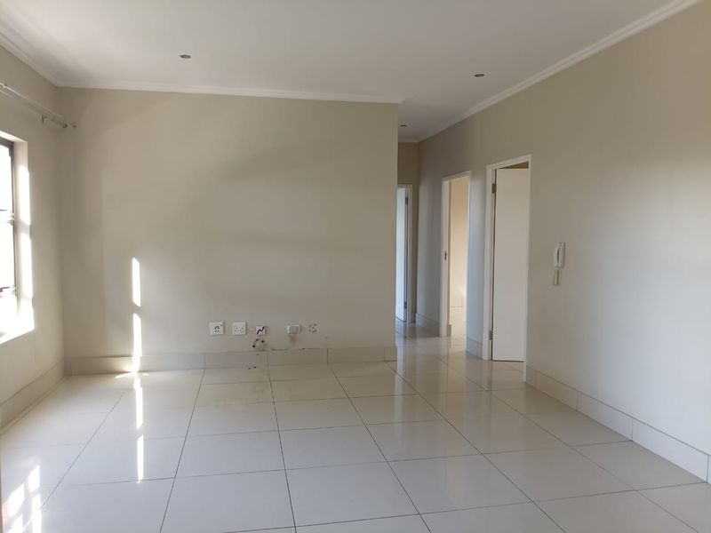 A bright, empty living area featuring neutral tiled flooring, recessed downlighting, and an integrated intercom system, providing a clean canvas for interior design.