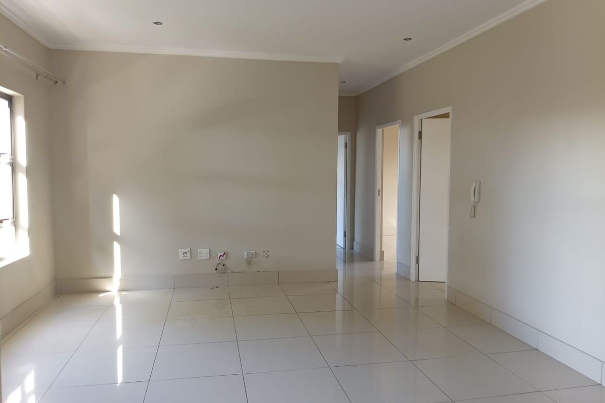 A bright, empty living area featuring neutral tiled flooring, recessed downlighting, and an integrated intercom system, providing a clean canvas for interior design.