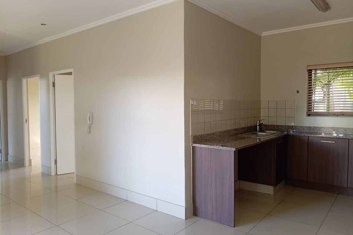 A clean, modern kitchen area featuring granite countertops, dark wood cabinetry, and neutral floor tiles, offering a functional and well-maintained space.